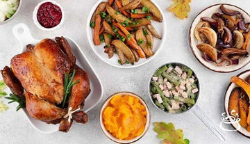 Christmas meal with roasted turkey, mashed sweet potatoes, sautéed vegetables, green beans, and cranberry sauce on white table