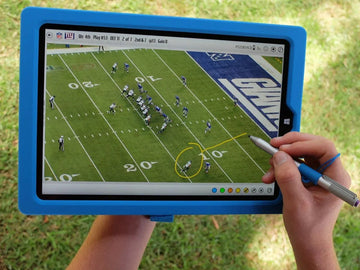 Hand using stylus on tablet showing football play analysis with yellow markings on field