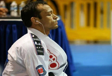 Brazilian Jiu-Jitsu athlete in white gi with patches, focused and listening to music before competition