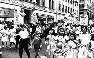Black and white photo of children marching in a Labor Day parade holding American flags and Local 91 ILGWU signs